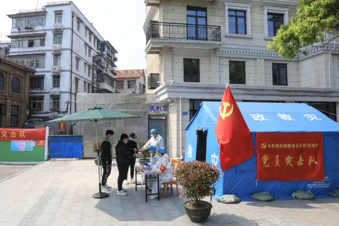 黨員突擊隊在小區防控點為出入群眾測量體溫，記錄信息。